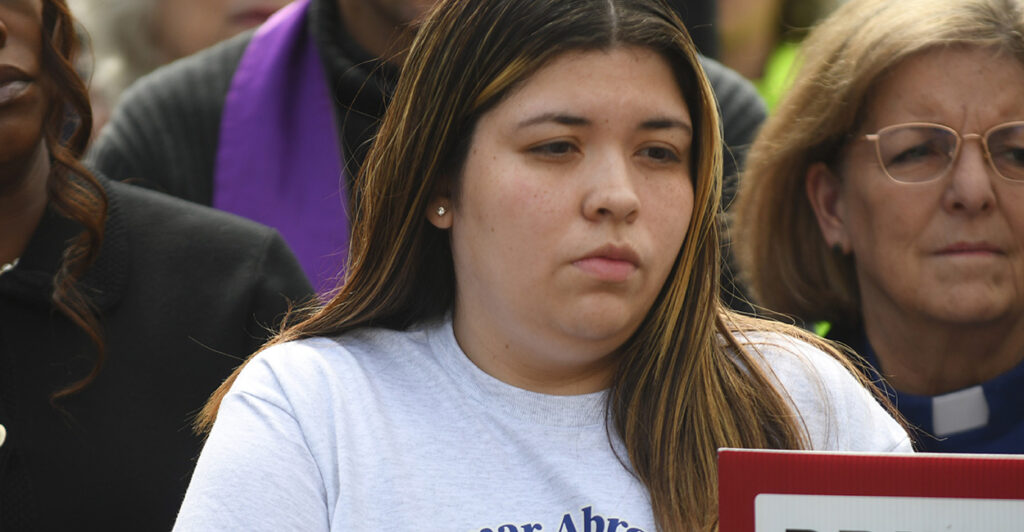 Jennifer Vasquez Sura stands in a crowd in a grey t-shirt.