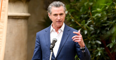 Gavin Newsom gestures while wearing a blue suit