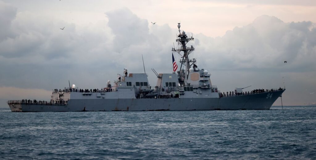 An Arleigh Burke-class U.S. Navy destroy is anchored off the coast of Turkey near dawn or sunset.