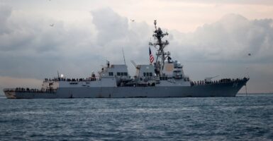 An Arleigh Burke-class U.S. Navy destroy is anchored off the coast of Turkey near dawn or sunset.
