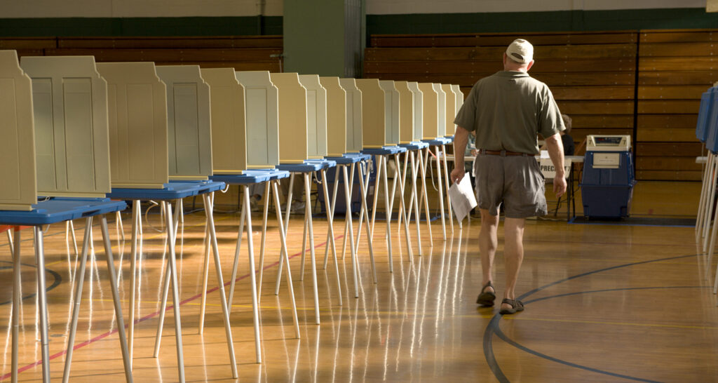 Solitary man walks past empty voting booths on way to cast his ballot.
