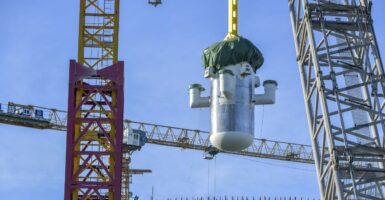 The silver pill-shaped core model of the world's first commercial small modular reactor is being lowered by a crane in Changiang, China.