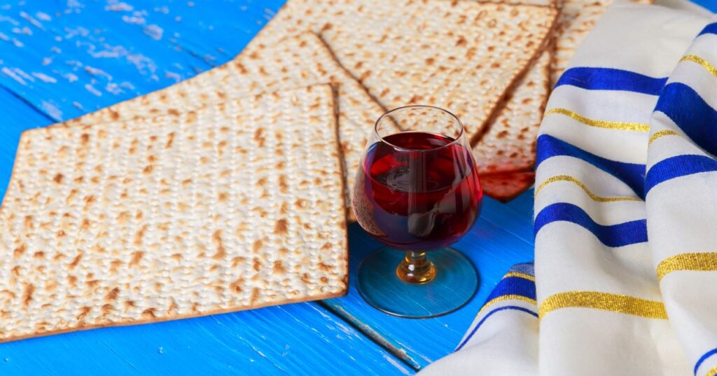 Passover matzah, wine and white cloth with blue and gold strips on a blue background