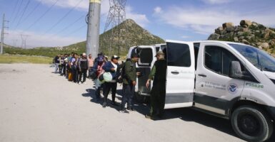 A line of migrants are processed by the US Border Patrol agents into a white van after crossing the U.S.- Mexico border.