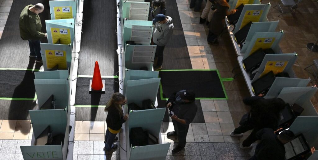 Overhead shot of three rows of booths at a polling center in Henderson, Nev., Election Day, 2024. Roughly half the booths are occupied. An orange cone sits in the middle of one aisle.