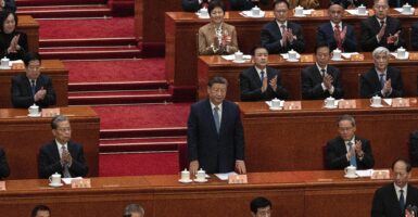 Chinese President Xi Jinping stands amid other Chinese Communist Party members, who applaud with assorted degrees of enthusiam.