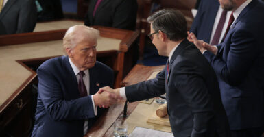 Donald Trump, in a darl blue suit, shakes hands with Mike Johnson, dressed in a dark grey suit.