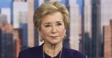 Close-up of Secretary of Education Linda McMahon, in a purple jacket, with image of New York skyline in background