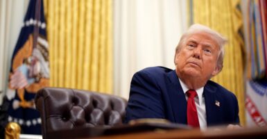 In a low-angle shot, President Donald Trump looks up from his Oval Office desk.