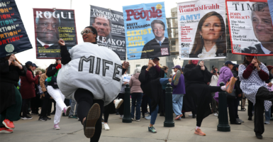 A woman wears a MIFE abortion pill costume outside the U.S. Supreme Court, along with other abortion supporting protesters with large placards with conservative Supreme Court justices' faces