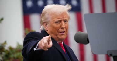 President Donald Trump pointing and speaking outside the White House in front of an American flag.