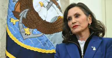 Michigan Gov. Gretchen Whitmer in the White House Oval Office with a U.S. Navy flag as backdrop