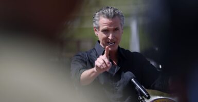 California Gov. Gavin Newsom points during and outdoor event announcing he's suing the Trump administration over tariffs.