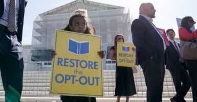 A somber-looking child holds a yellow sign with blue lettering reading "Restore the Opt-Out" with the scaffold-coffered Supreme Court behind her.