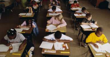 Young students about 10-12 years old sit intently at their desks taking a standardized test.