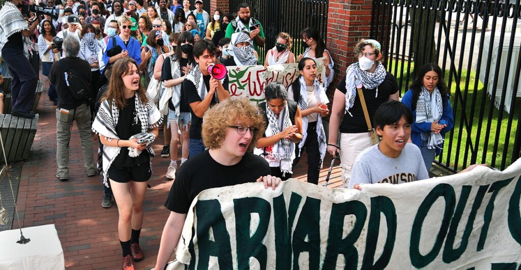 Pro-Palestinian protesters carry signs as they walk down a street.