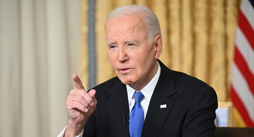 Joe Biden in a black suit points at the camera