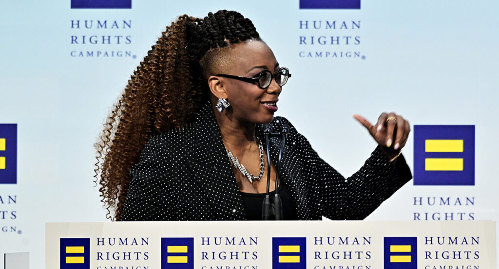 Human Rights Campaign President Kelley Robinson gestures while in a black suit coat with