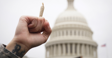 An activist holds up a marijuana cigarette against the backdrop of the U.S. Capitol Building Dome.