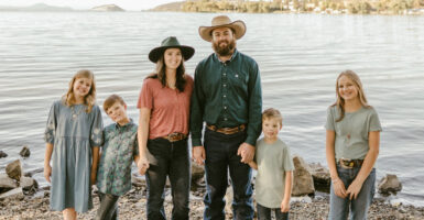 Fifth-generation farmer Rodney Cheyne with his wife in cowboy hats and their four young children standing in front of a large lake