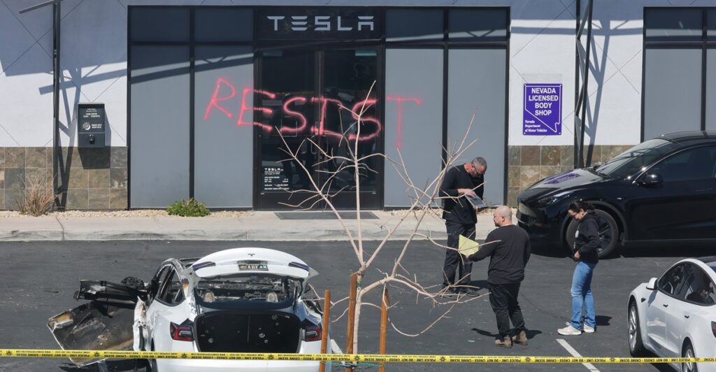 Investigators are at the parking lot of a Tesla store that was vandalized as the word "resist" is written in red spray paint on the building.
