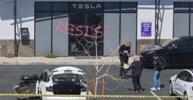 Investigators are at the parking lot of a Tesla store that was vandalized as the word "resist" is written in red spray paint on the building.