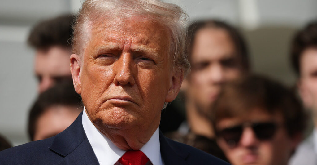 President Donald Trump looks to the side in a red tie.