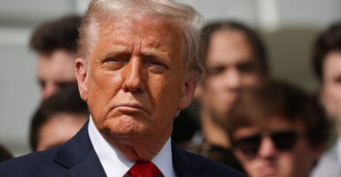 President Donald Trump looks to the side in a red tie.