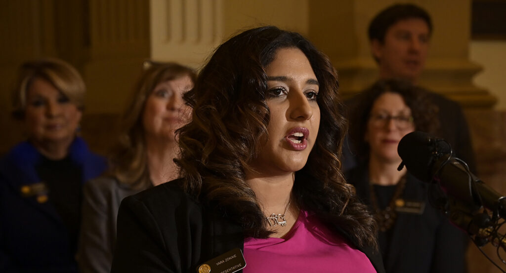 Yara Zokaie wearing a name tag and a pink blouse with a few female Democrats behind her