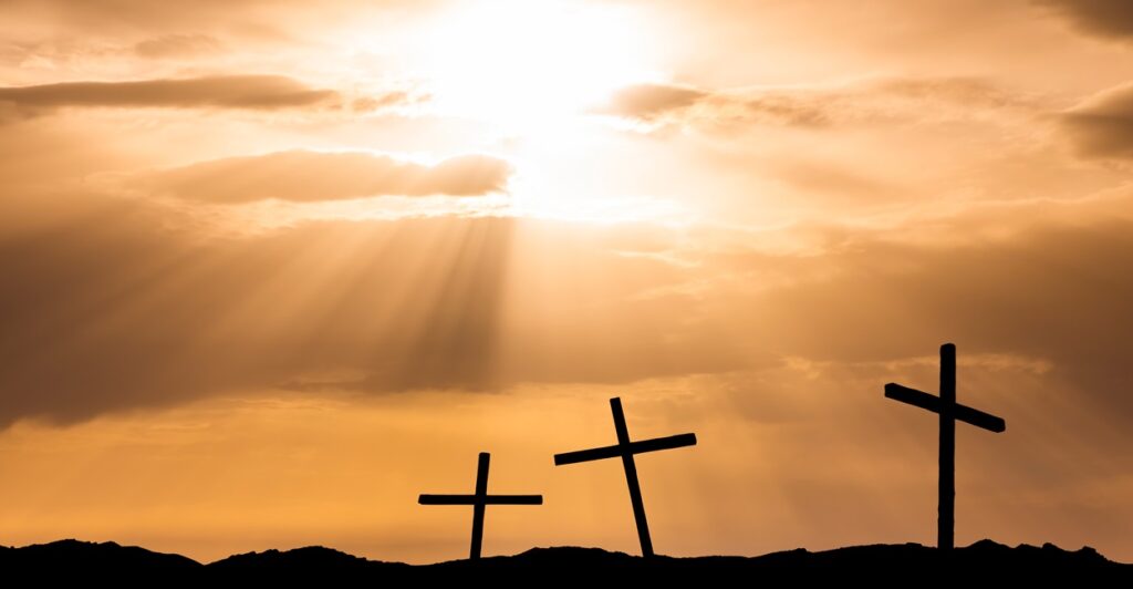 Three crosses are shown with the sun setting in the background.