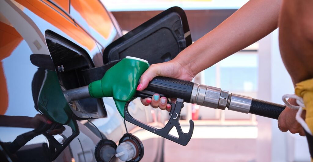 A person holds a gas pump while filling up a car with gas.