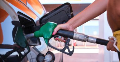 A person holds a gas pump while filling up a car with gas.