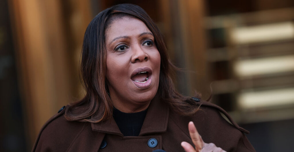 New York Attorney General Letitia James in a brown trenchcoat speaking at a podium and pointing her finger
