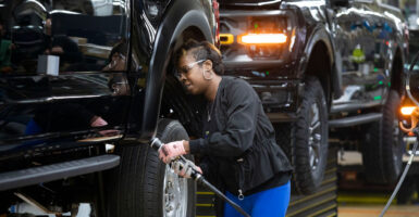 a black woman working on black pickup trucks in a Ford production line