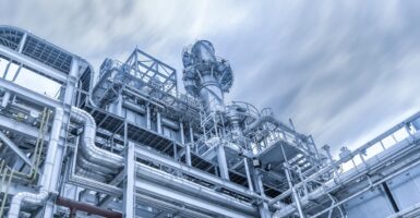 The steel pipelines of a natural gas power plant are shown with a blue sky in the background.