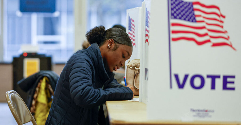 a young black woman sits down to vote and write her choices down on paper