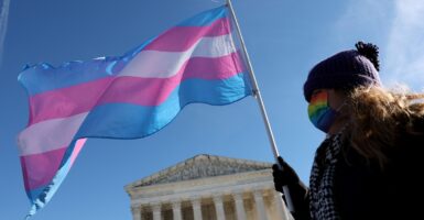 A transgender rights activist holds a transgender flag while walking.