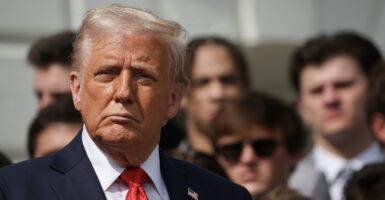 Donald Trump stands at a press conference and looks straight ahead.