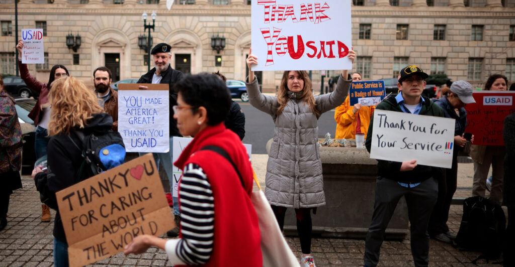 Supporters hold signs as former USAID employees are terminated after the Trump administration dismantled the agency.