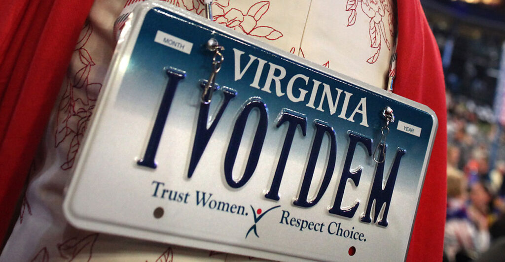 a woman wears a Virginia license plate on her back that says IVOTDEM