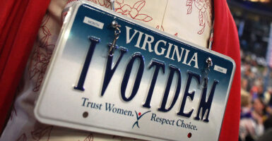 a woman wears a Virginia license plate on her back that says IVOTDEM