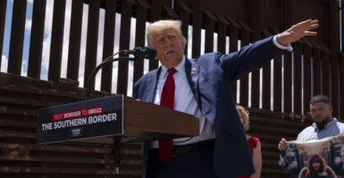 Then-candidate Donald Trump at the border wall in 2024, giving speech, and pointing off to his left.