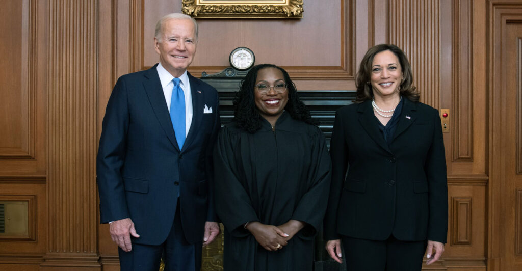A robed Justice Ketanji Brown Jackson flanked by President Biden and Vice President Harris.