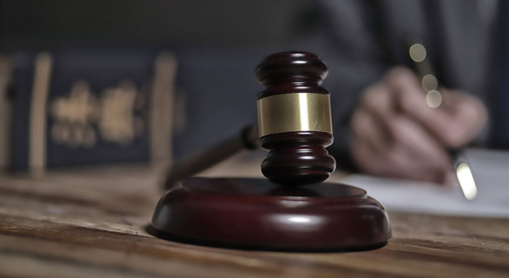 A gavel in a law office, with lawyer working in background out of focus.