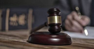 A gavel in a law office, with lawyer working in background out of focus.