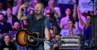Bruce Springsteen with acoustic guitar gestures during a 2024 rally for Kamala Harris.