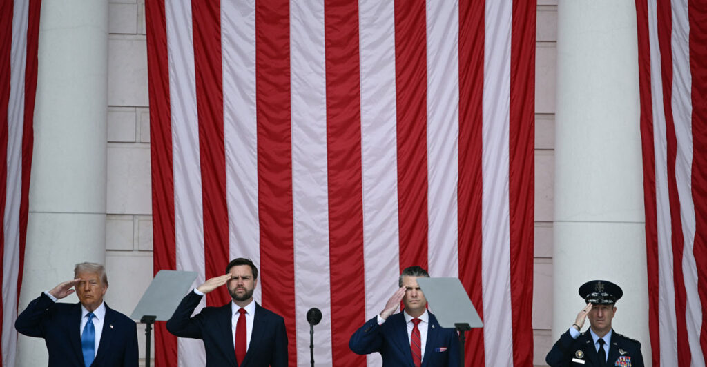 President Trump, VP JD Vance, Secretary of Defense Pete Hegseth salute against the backdrop of a large American flag in the amphitheater of the Tomb of the Unknown Soldier at Arlington National Cemetery, May 26, 2025.