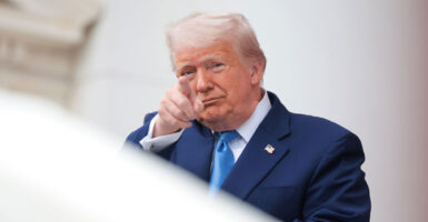 A grinning President Donald Trump points toward camera.