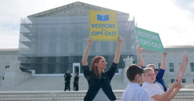 A female demonstrator holds up sign reading "Restore the Opt Out" in front of the U.S. Supreme Court building.