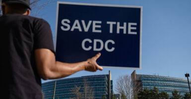 People protesting personnel cuts at the Centers for Disease Control hold signs outside the organization's Atlanta, Georgia, headquarters on March 12.
